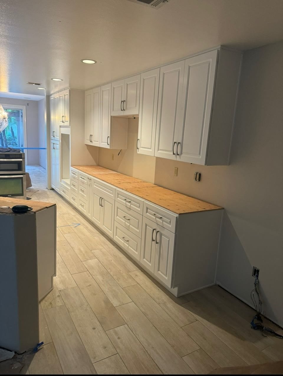 White shaker cabinets with butcher-block countertops being installed