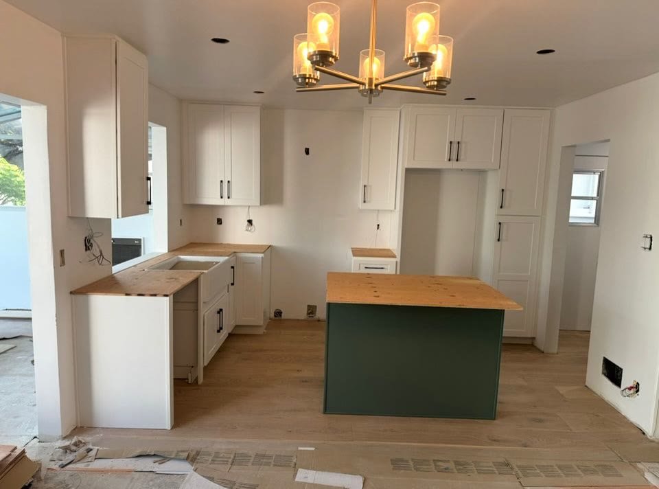 Green cabinets with wood island mid-installation