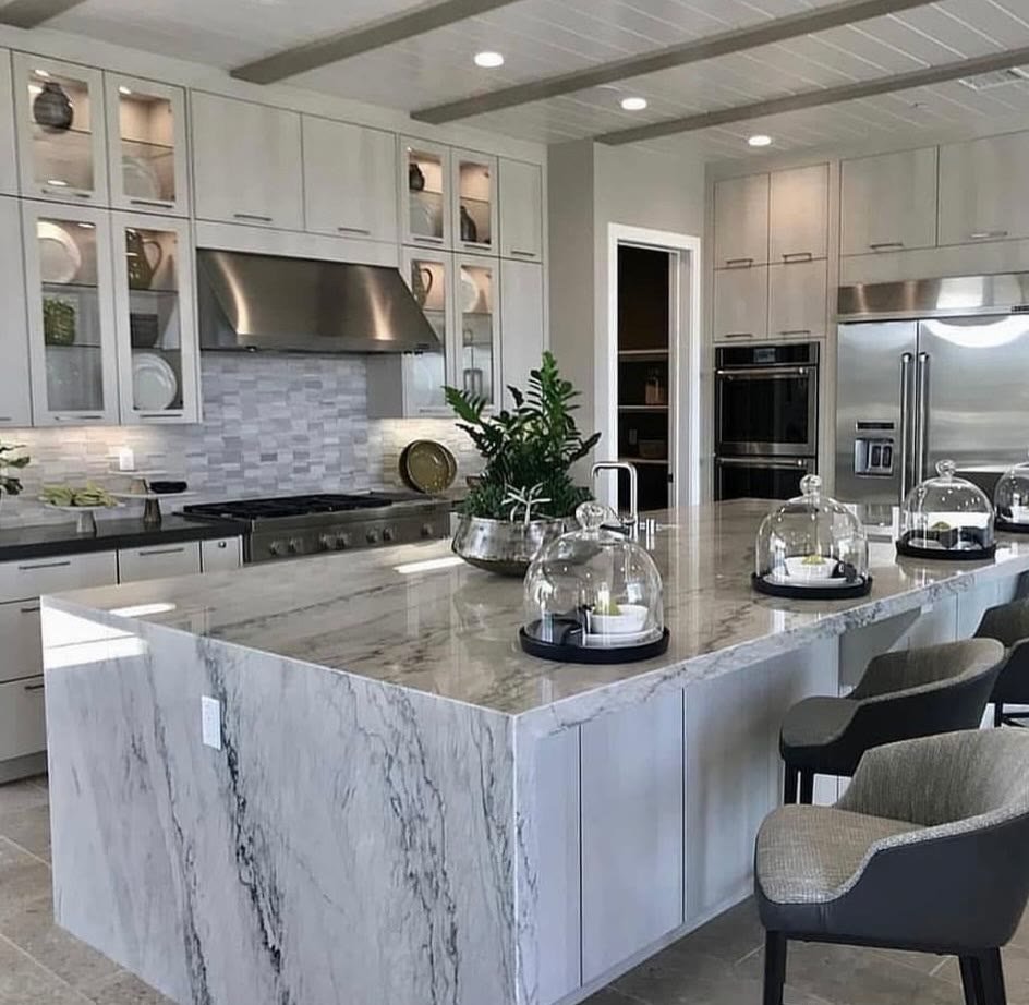 Completed white kitchen with marble backsplash and island seating